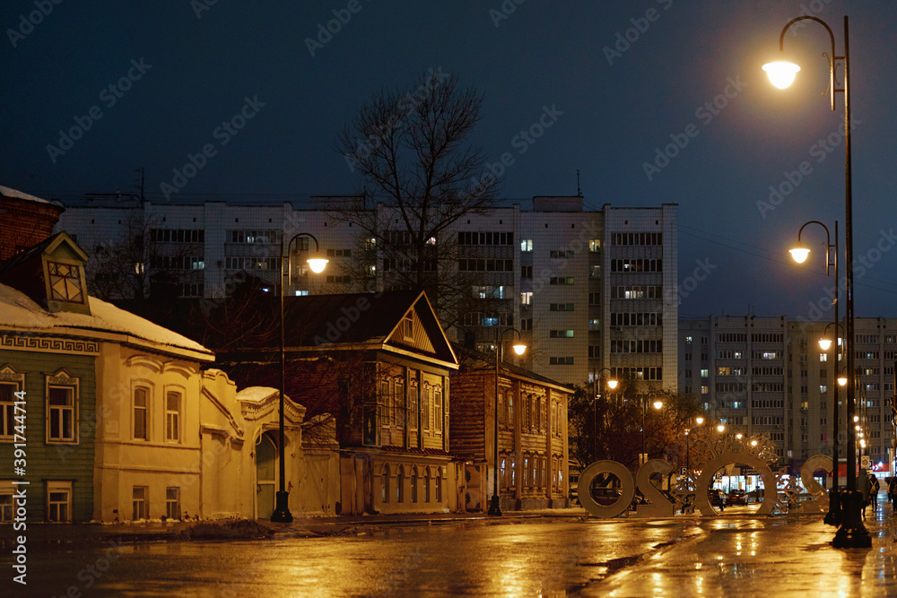 Evening street with old wooden and new houses. Art-object «2020» on the back side. Lights are burning. KAZAN, RUSSIA — JANUARY 16 2020