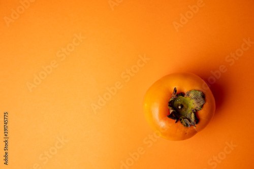 Persimmon fruit on orange background