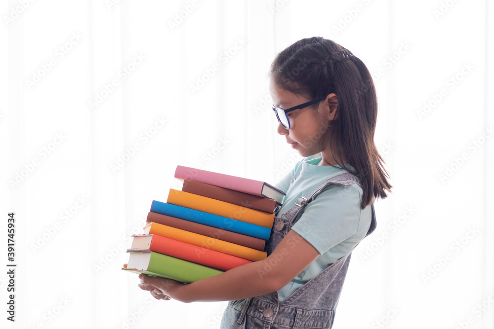 Adorable Asian smart girl in casual jean hold stack of books, adorable intelligent school girl primary looking her many book with happy, girl study at home social distance back to school concept Adorable Asian smart girl in casual jean hold stack of books, adorable intelligent school girl primary looking her many book with happy, girl study at home social distance back to school concept