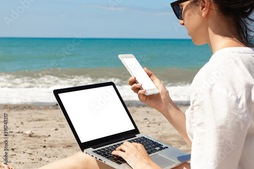 Young woman using laptop computer on a beach. Vacation lifestyle communication. Freelance work concept