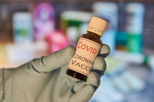Hand with blue glove holding a flask with vaccine. Coronavirus vaccine in a flask. Biontech vaccine. Pfizer vaccine. Vaccine candidate. Vial with vaccine. Moderna vaccine.