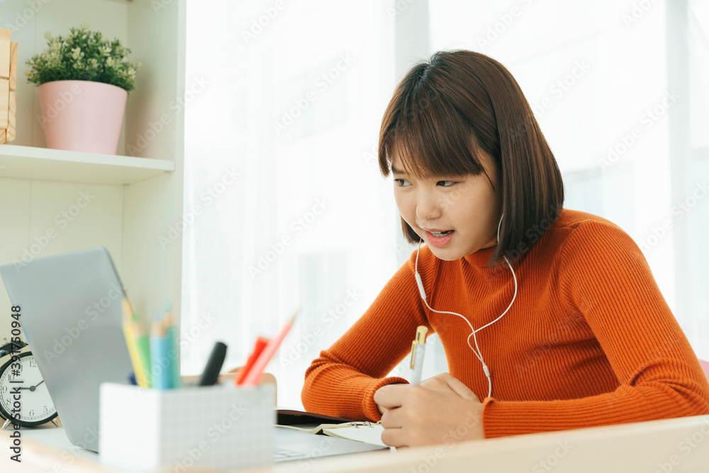 Beautiful young asian thai black short hair woman learning from home study online on laptop and wearing earphone.
