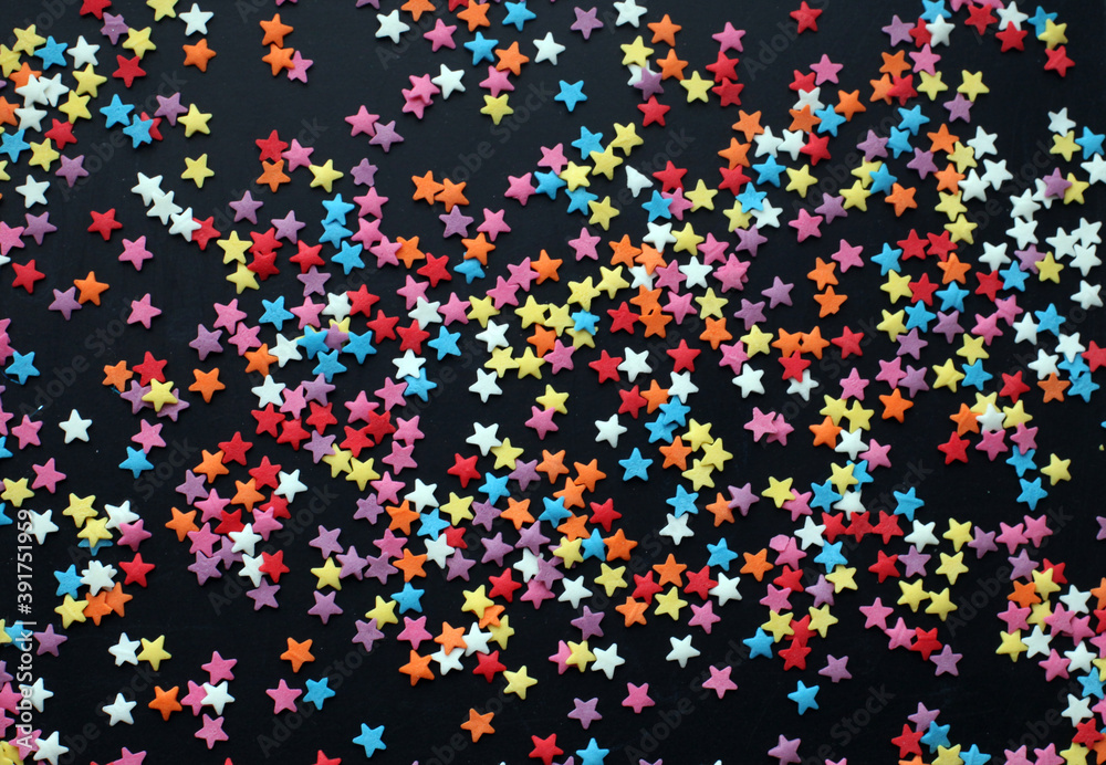 multicolored confetti stars on dark background. Festive background. 