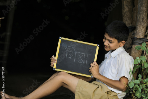 Cute Indian little child studying at home and showing writing some word in marathi language photo