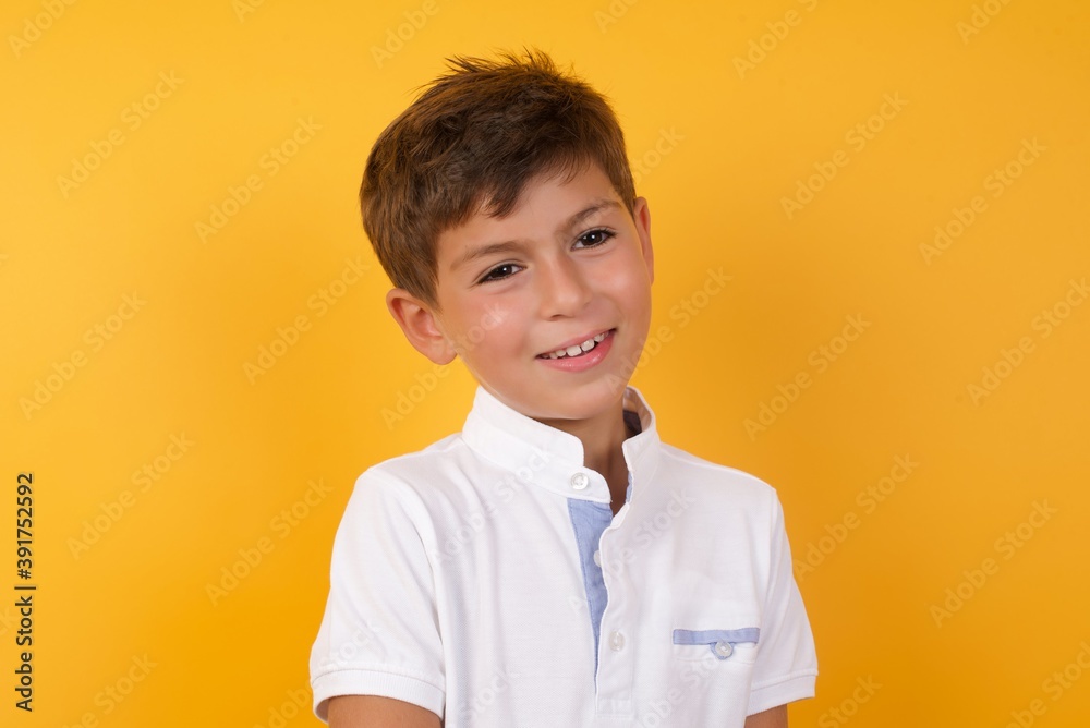 Unhappy Cute Caucasian little boy standing against yellow background crying while posing at camera whipping tears with hand. Unhappy Cute Caucasian little boy standing against yellow background crying while posing at camera whipping tears with hand.