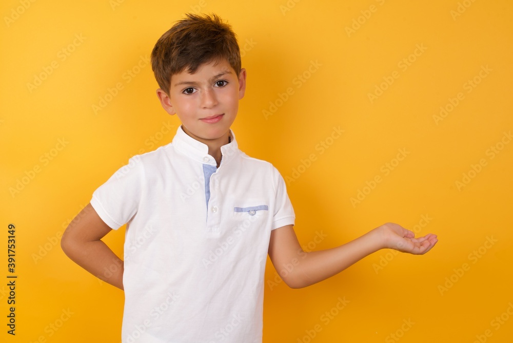 Portrait of Cute Caucasian little boy standing against yellow background with arm out in a welcoming gesture. Portrait of Cute Caucasian little boy standing against yellow background with arm out in a welcoming gesture.
