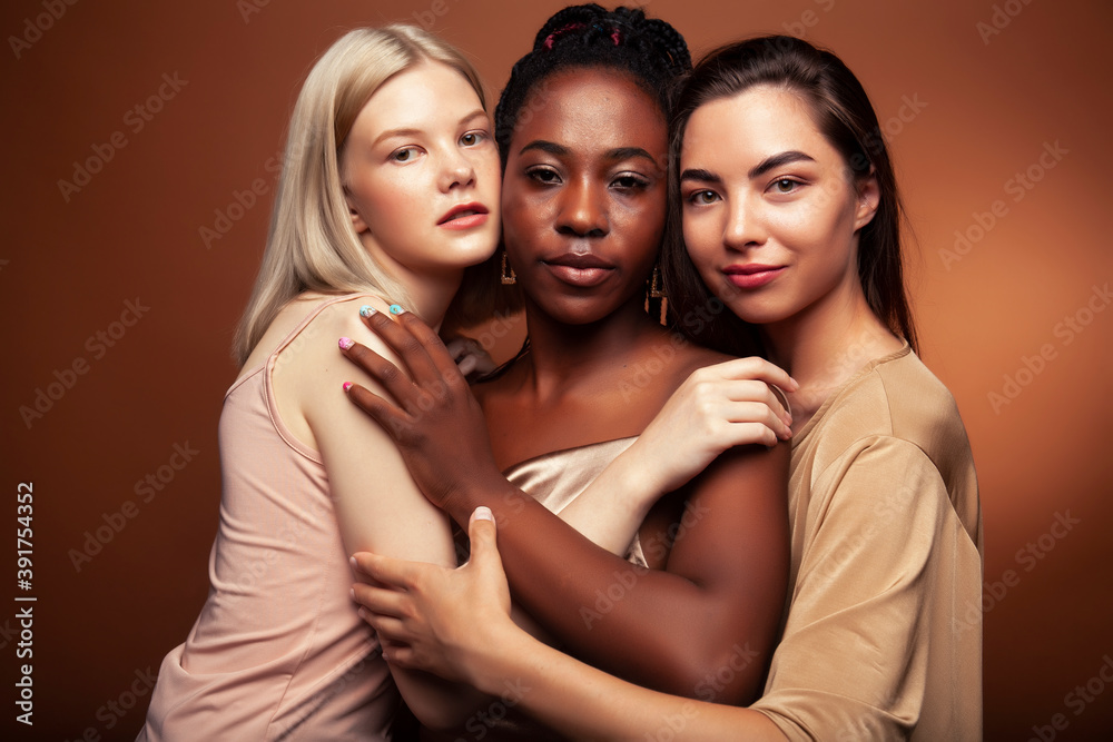 young pretty asian, caucasian, afro woman posing cheerful together on brown background, lifestyle diverse nationality people concept young pretty asian, caucasian, afro woman posing cheerful together on brown background, lifestyle diverse nationality people concept