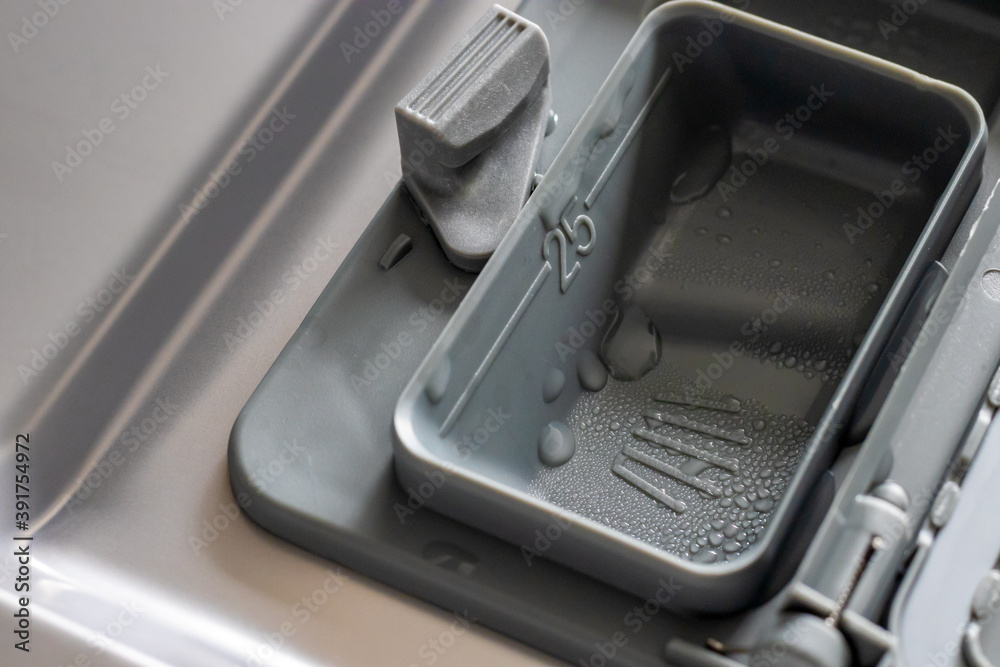 close up opened dishwasher detergent dispenser with water drops
