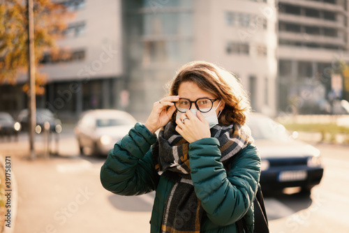 Portrait of a beautiful young European woman wearing a protective mask on a city street. Antiviral measures in a pandemic, health and safety new normal life