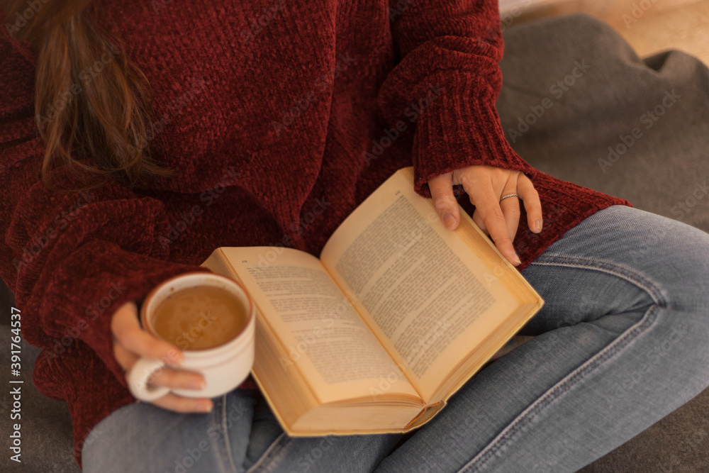Obraz premium pretty young woman reading a book and drinking coffee happily, sitting on some stairs