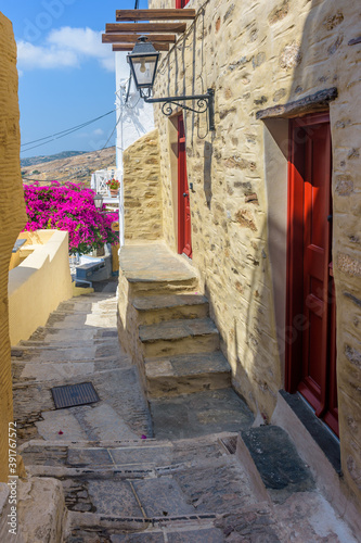Traditional cycladitic   alley with narrow street, whitewashed  houses and a blooming bougainvillea, in ano Syros Greece © valantis minogiannis