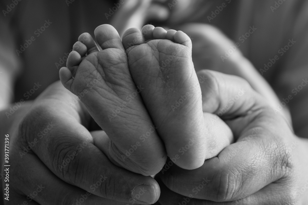 Parent holding in the hands feet of newborn baby..