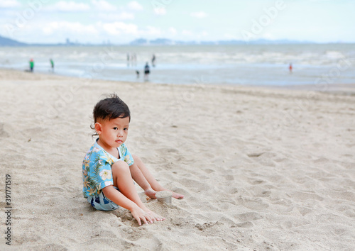 Portrait of little asian baby boy having fun with sand at the beach.