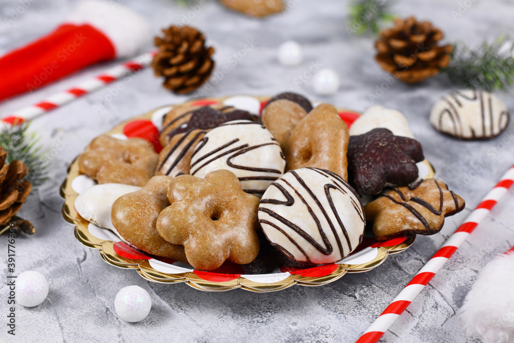 German gingerbread cookies with sugar and brown and white chocolate glazing in heart and star shape called 'Lebkuchen' on striped plate surrounded by seasonal Christmas decoration