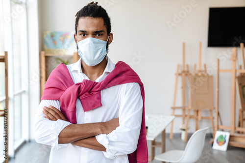 Young african american guy in face mask posing with arms crossed