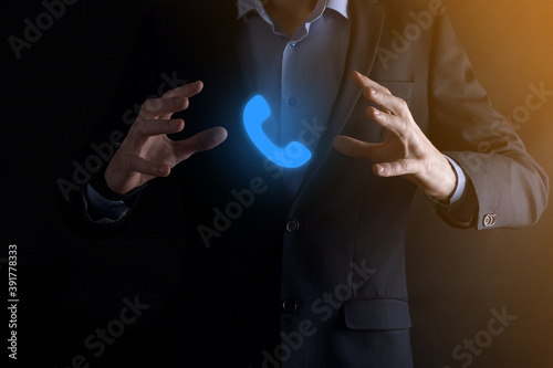 Businessman in suit on black background hold phone icon.Call Now Business Communication Support Center Customer Service Technology Concept.