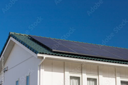 日本の住宅の屋根に設置された太陽光発電パネルの風景