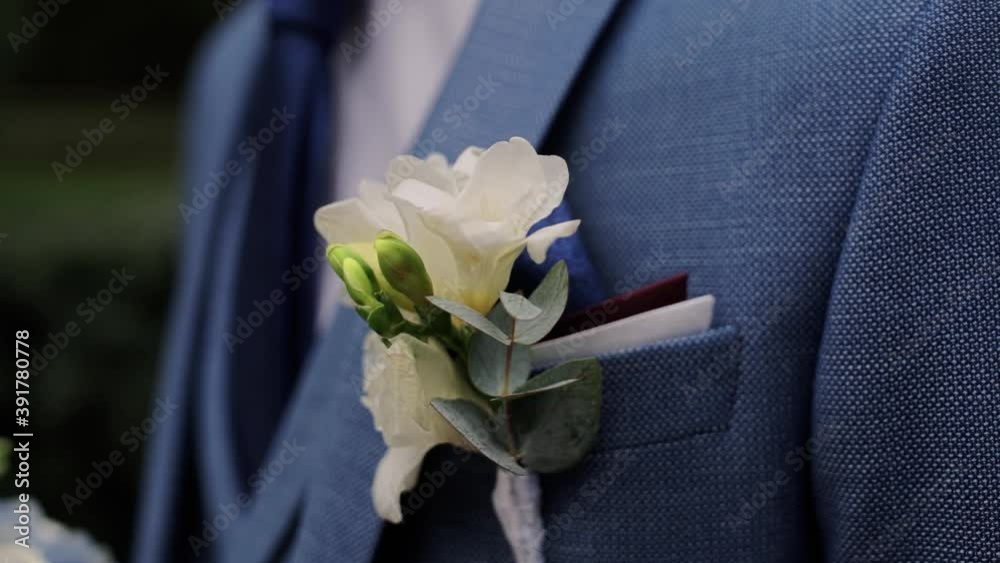 groom's boutonniere of flowers on a blue jacket