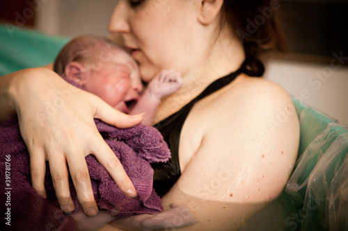 Mother Holding Newborn Baby in Birthing Pool After Home Birth photo