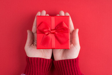 Giving present to friend concept. Top above overhead close up first person view photo of woman holding small box with little bow isolated bright color background