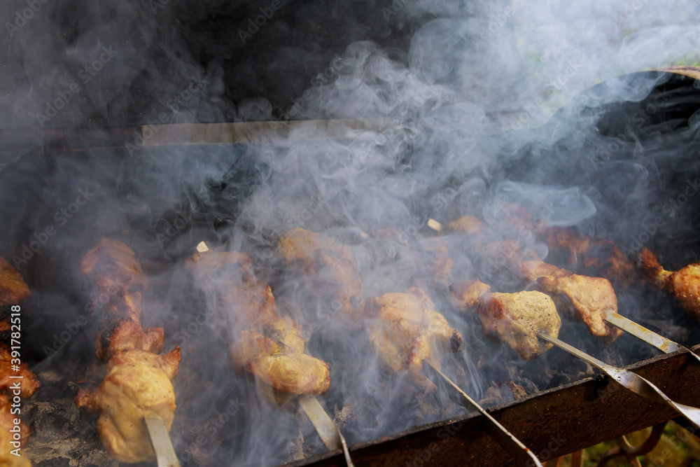 Meat with smoke on skewers is grilled with burning charcoal. Soft focus. Meat with smoke on skewers is grilled with burning charcoal. Soft focus.