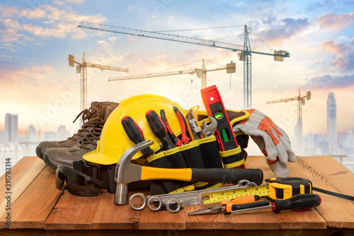 Yellow helmet for construction work and tools with a background crane.