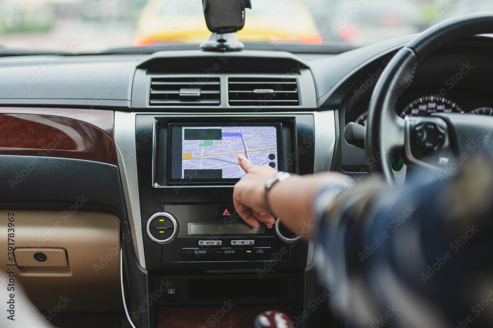 Woman driving car with hand touching navigation on monitor screen.