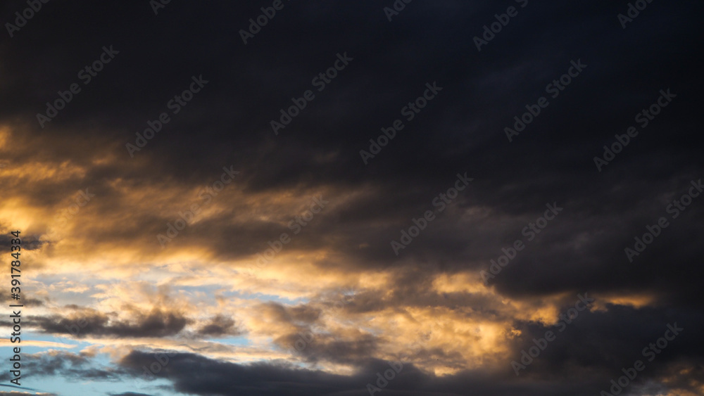 Naklejka premium Coucher de soleil et reflets jaunâtres sous un gros nuage à la base bien sombre