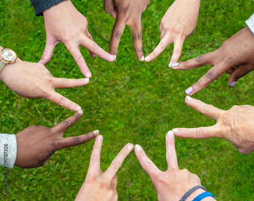 Black and white people forming nine pointed star with their fingers. photo