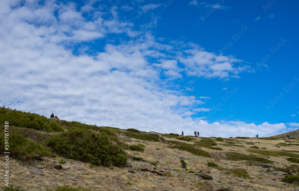 Hikers climbing the mountain on a trail on a sunny day. Ascent to Peñalara in the Sierra de Madrid.