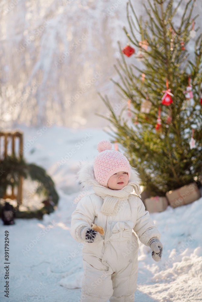 Little girl toddler in warm clothes walks in the winter forest against the background of New Year's decorations
Little girl toddler in warm clothes walks in the winter forest against the background of New Year's decorations