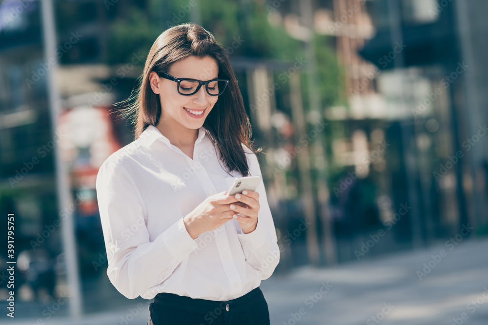 Photo of adorable charming young lady dressed white formal shirt glasses smiling looking typing modern gadget outside