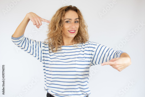 Beautiful curly hair young woman wearing casual t-shirt over isolated background pointing fingers to camera with happy and funny face. Good energy and vibes.