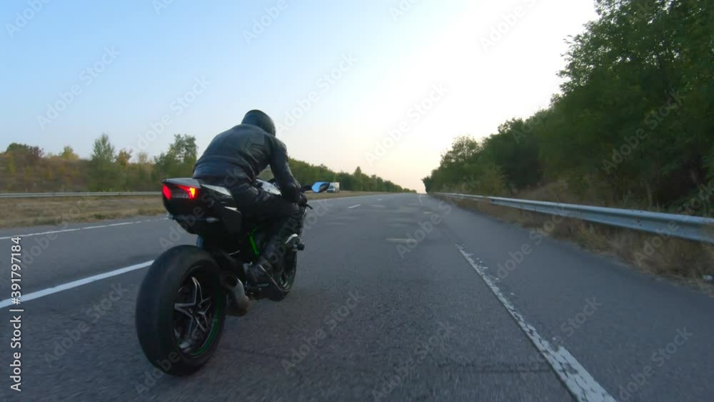 Follow to motorcyclist riding on modern sport motorbike at highway. Biker racing his motorcycle on country road. Guy driving bike during trip. Concept of freedom and adventure at journey. Aerial shot Follow to motorcyclist riding on modern sport motorbike at highway. Biker racing his motorcycle on country road. Guy driving bike during trip. Concept of freedom and adventure at journey. Aerial shot