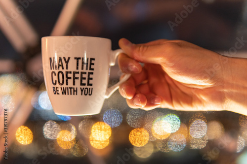 Foto A hand holding a coffee cup is in focus with bokeh lights in the background, and has a funny quote that is a play on a famous sci-fi movie line