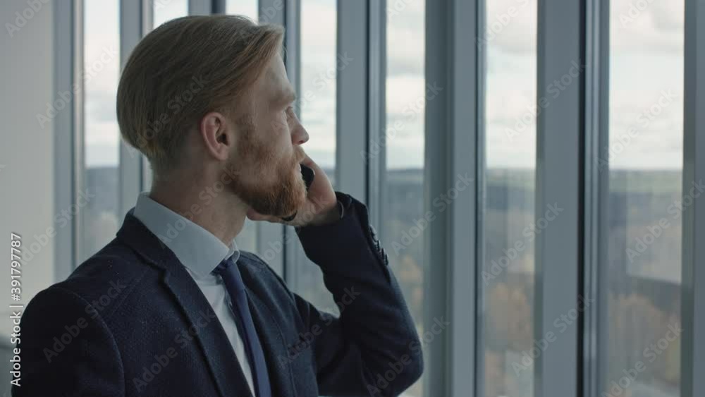 Portrait of serious middle age businessman answering phone call modern workplace. Closeup handsome male employee talking on smartphone in office. Confident business man working at office Portrait of serious middle age businessman answering phone call modern workplace. Closeup handsome male employee talking on smartphone in office. Confident business man working at office