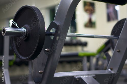 A barbell with pancakes installed on a bench for training biceps. Barbell and pancakes strength training. Gym.