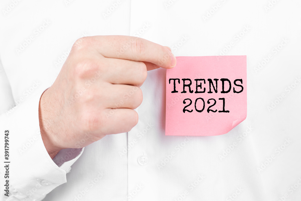 Man attaches a red sticker with text TRENDS 2021 overlay to his white shirt Man attaches a red sticker with text TRENDS 2021 overlay to his white shirt