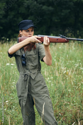 Woman holding a gun in front of him taking aim hunting lifestyle green leaves green 