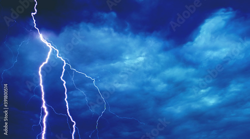 Lightning in the dark blue sky. Stormy sky. Thunderstorm on a dark blue background. Lightning flashes across the night sky. Natural disaster. Hurricane, Typhoon, tornado, storm.