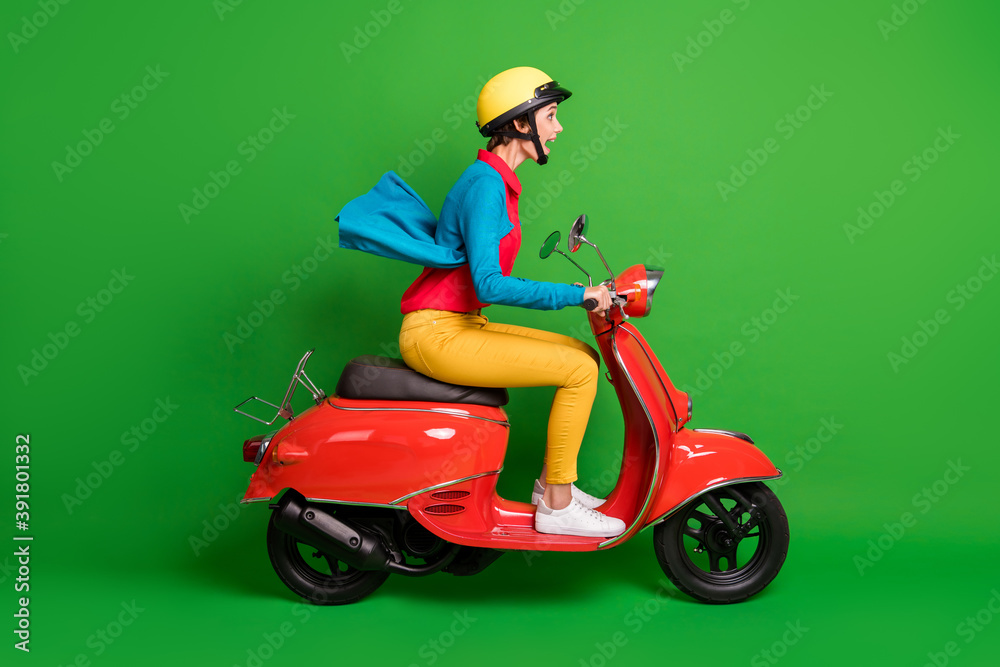 Full size profile side photo of young shocked amazed girl ride fast on red motorcycle isolated on green color background Full size profile side photo of young shocked amazed girl ride fast on red motorcycle isolated on green color background