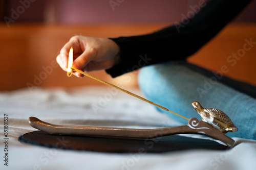Woman lighting an incense stick. Yoga with incense.
