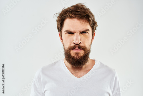 Bearded man gesturing with hands cropped view white t-shirt studio emotion light background