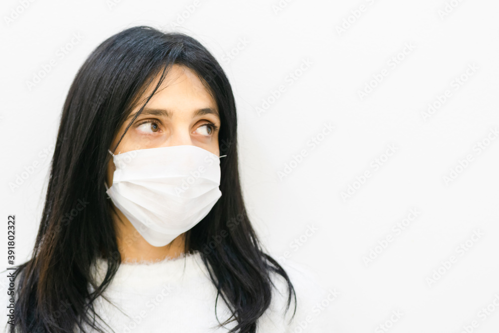 Close up of Young caucasian woman wearing white mask and looking to the right side of white blank space area. Close up of Young caucasian woman wearing white mask and looking to the right side of white blank space area.