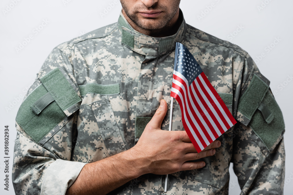 Fototapeta premium cropped view of patriotic military man in uniform holding american flag isolated on white