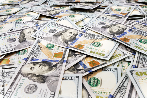 Pile of dollars lies on the table. One hundred dollar bills dumps on table. Background for design from lot of money. Close-up. Side view