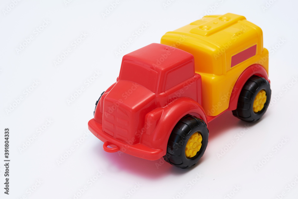 Colorful Children's toy car truck with a red cab and a yellow plastic body on a white background. Flat lay. Copy space.
