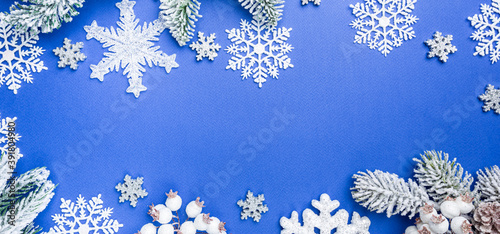 Christmas holidays composition with white christmas decorations and fir tree branches on blue background with copy space, top view