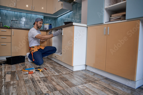 Young caucasian worker measuring drawer in kitchen furniture