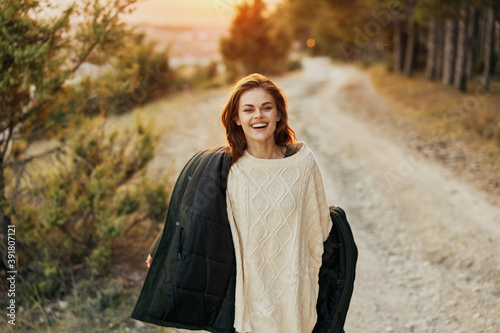 woman in a jacket walking along the road near the forest